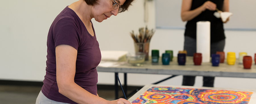 woman painting on an intuitive painting on a table