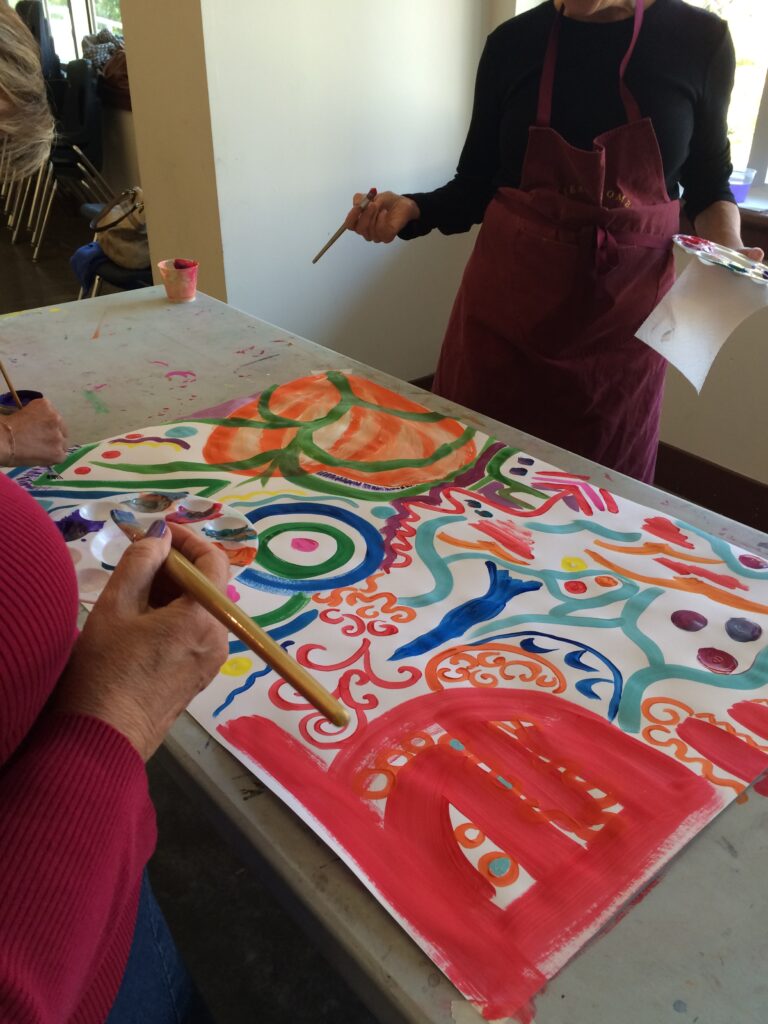 intuitive painting workshop in the Yellow Barn with students painting on a large piece of paper on an art table