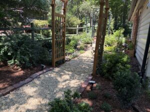 Arbor with river rock path in a lush garden.