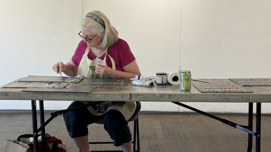 Female student mixing paint colors sitting at a table
