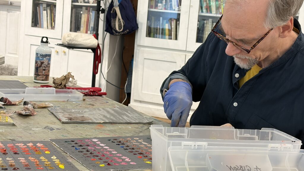 Male student intently mixing colors sitting at an art table.