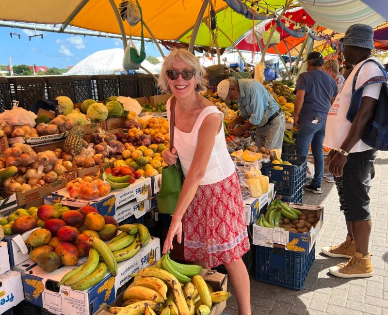 Elisabeth Vismans in Curaçao Elisabeth Vismans dressed in white sleeveless top and red skirt standing on a colorful fruit market in Curaçao